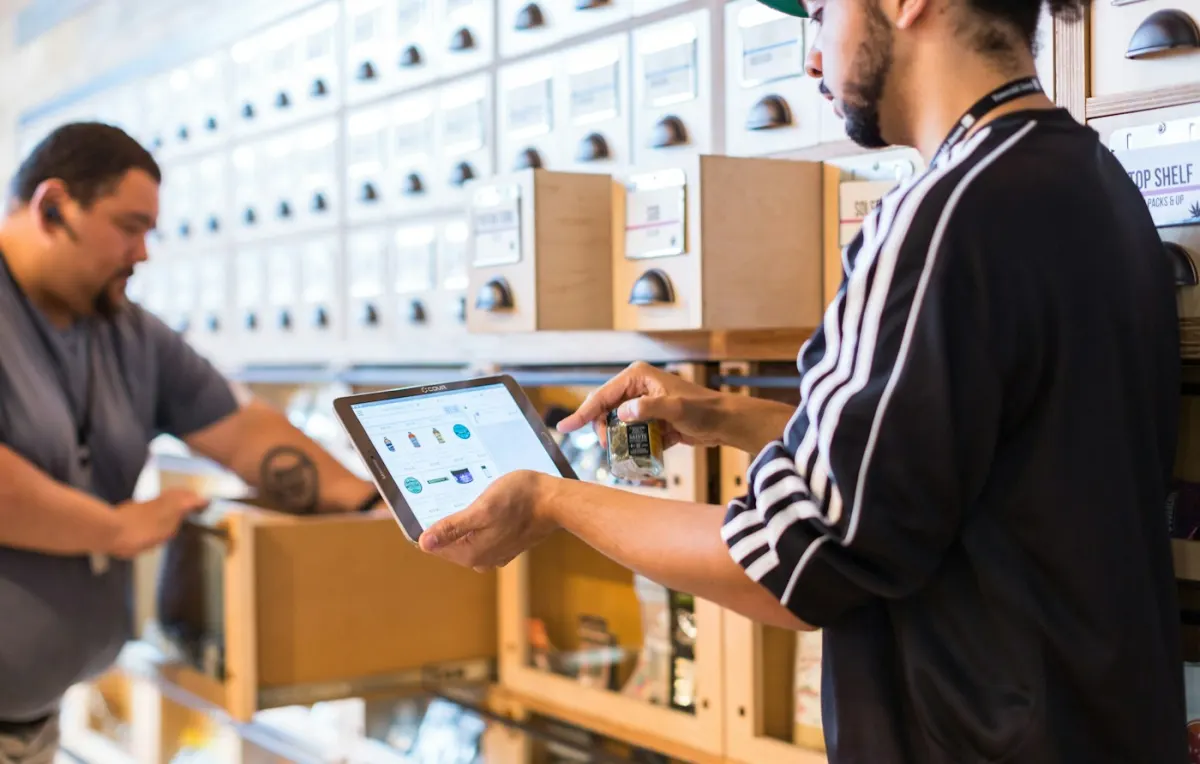 Two team members reviewing an order on a tablet among stocked shelves